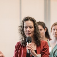 Woman speaking to crowd holding a microphone